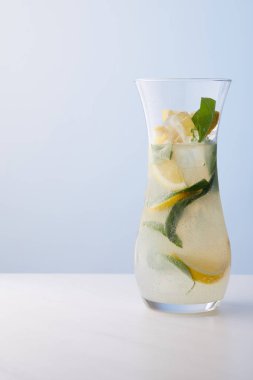 Nane yaprakları, buz ve limon dilimleri üzerinde mavi arka plan ile limonata sürahi 