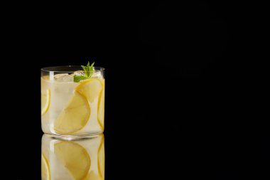 single glass of fresh lemonade on reflective surface isolated on black clipart