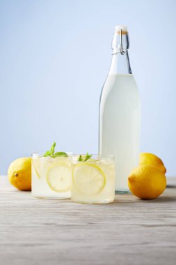 bottle and glasses of fresh italian limoncello on wooden tabletop clipart
