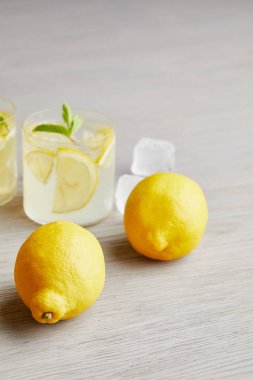 lemonade with ripe lemons on wooden surface 