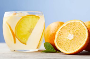 glass of fresh lemonade with ripe oranges on wooden table clipart