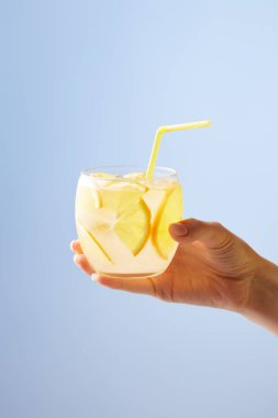 cropped shot of woman holding glass of lemonade isolated on blue clipart