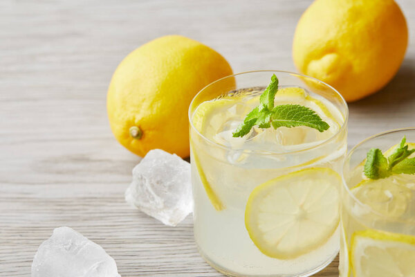 охлажденные лимонадные бокалы с созревшими лимонами на деревянной поверхности
 