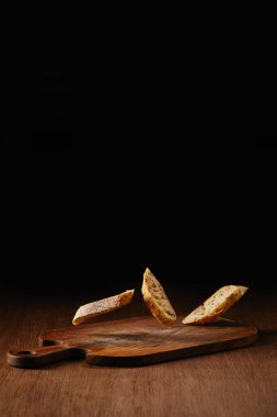 Slices of wholegrain bread falling on wooden table surface clipart