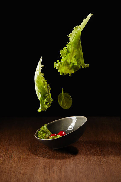 Fresh organic salad flying above wooden table surface