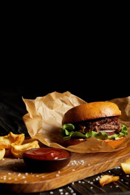Hamburger ve kızarmış patates tuz ve ahşap tahta üzerinde sos ile