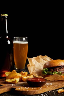 Hamburger and french fries served with cold beer on wooden board clipart