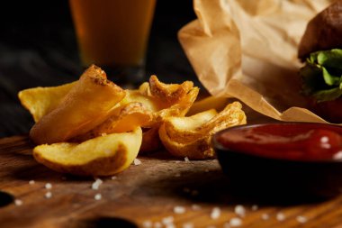 Hamburger ve kızarmış patates ahşap tahta üzerinde sos ile servis