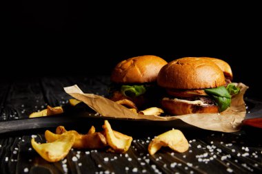 Abur cubur hamburger ve patates kızartması ahşap masa üzerinde dağınık tuz ile