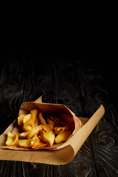 Golden french fries in craft paper on wooden table