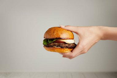 Gri arka plan üzerinde el sıcak lezzetli burger