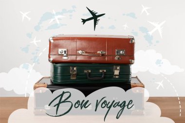 Stacked old leather travel bags with airplanes and Bon voyage (have a nice trip) inspiration clipart