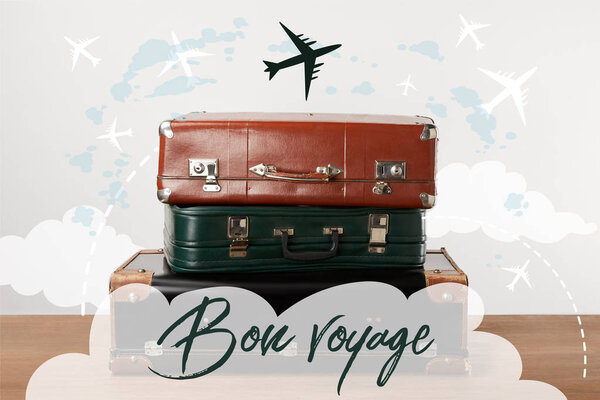 Stacked old leather travel bags with airplanes and Bon voyage (have a nice trip) inspiration