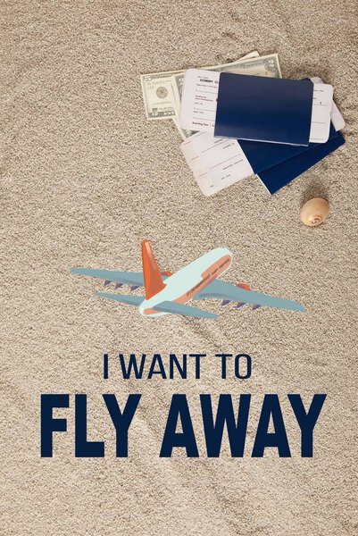 top view of arranged passports, tickets and dollar banknotes on sand with "I want to fly away" lettering and airplane illustration