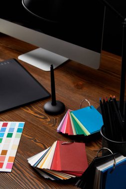 ahşap yüzey üzerinde renkli palet, grafik tablet ve bilgisayar ekranı ile grafik tasarımcı çalışma alanı'nın görünümünü kapat