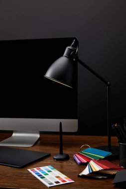 ahşap yüzey üzerinde renkli palet, grafik tablet, bilgisayar ekranı ve lamba ile grafik tasarımcı çalışma alanı'nın görünümünü kapat