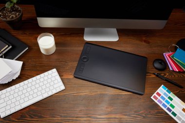 ahşap masa üzerinde palet, süt, grafik tablet ve bilgisayar ekranı ile grafik tasarımcı çalışma alanı'nın görünümünü kapat