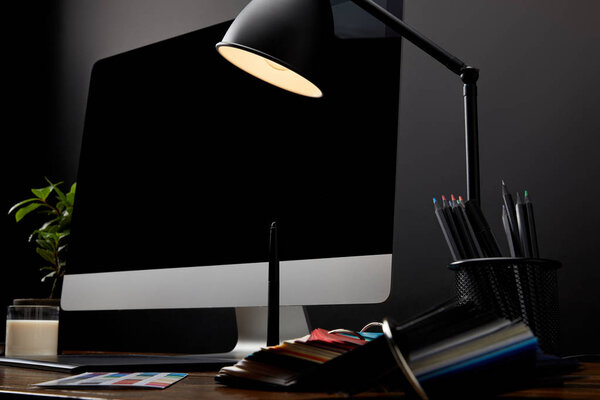 close up view of graphic designer workplace with colorful pallet, graphic tablet, blank computer screen and lamp on wooden surface
