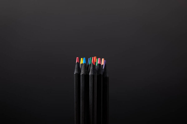 close up view of arranged pencils on black wall backdrop