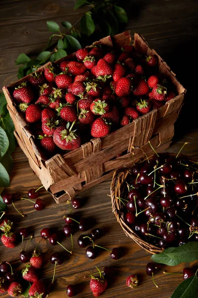 high angle view of cherries and strawberries in basket and box on wooden surface
