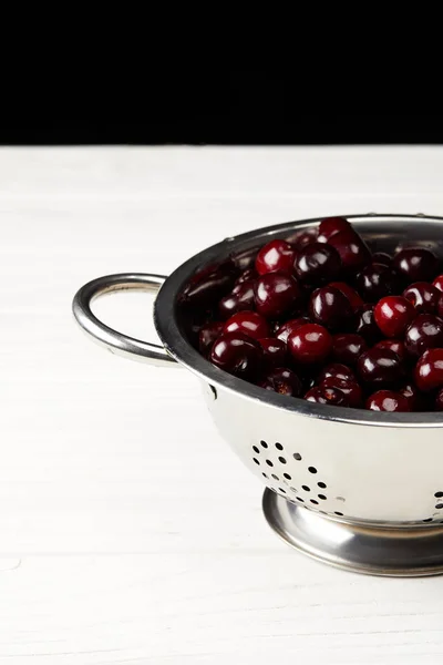 Merah Matang Ceri Manis Colander Logam Pada Permukaan Kayu Putih — Foto Stok Gratis