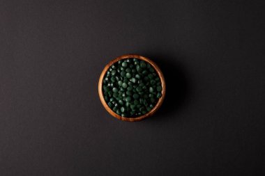 spirulina hapları yığını ile ahşap kase üstten görünüm gri masada 