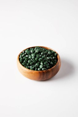 spirulina hapları gri arka plan üzerine yığını ile ahşap kase 