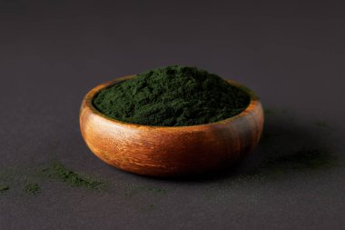 spirulina yosun toz gri masa üzerinde ahşap kase 