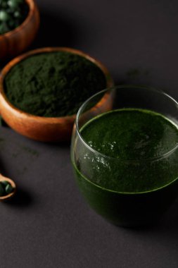 spirulina tozu ve gri tablo haplarla spirulina ile tahta kaşık, bardak taze yüzlü spirulina, üzerinden seçici odak kaseler 