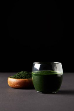 Cam ve spirulina tozu siyah arka plan üzerine ahşap kase taze spirulina içki 