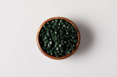 spirulina hapları yığını ile ahşap kase üstten görünüm gri masada