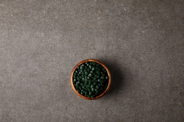 spirulina hapları yığını ile ahşap kase üstten görünüm taş masada 