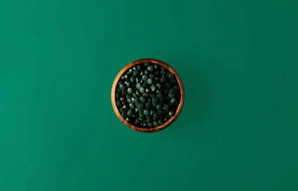 Widok Góry Drewniane Miski Stos Tabletek Spirulina Zielonym Tle — Zdjęcie stockowe