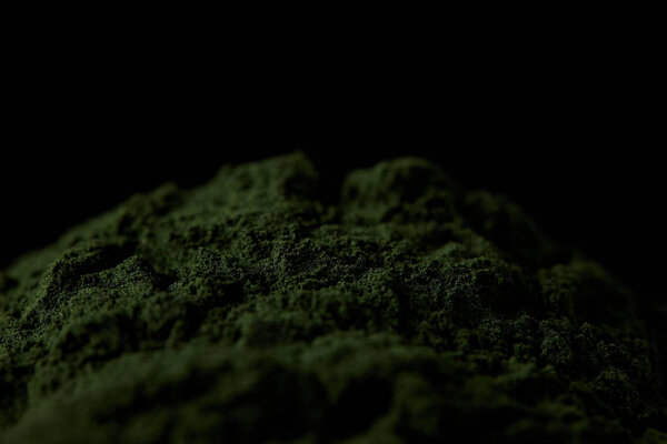selective focus of spirulina algae powder isolated on black background 
