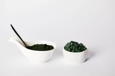 kaşık, spirulina tozu ve gri arka plan üzerinde kaseler spirulina hap 