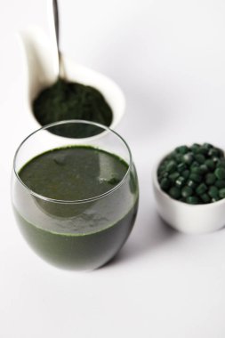 Cam, spirulina tozu ve spirulina hapları kase taze spirulina içki görünümü gri arka plan üzerine kadar kapatın 
