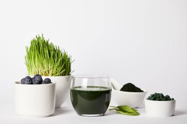 spirulina, spirulina çim ve yaban mersini, bardak taze güler yüzlü bırakır, spirulina tozu ve spirulina hapları gri arka plan üzerinde kaseler 