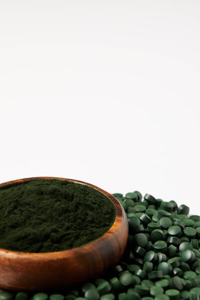 close up view of spirulina algae powder and spirulina pills isolated on grey background 