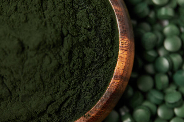 selective focus of spirulina pills and spirulina powder in bowl 