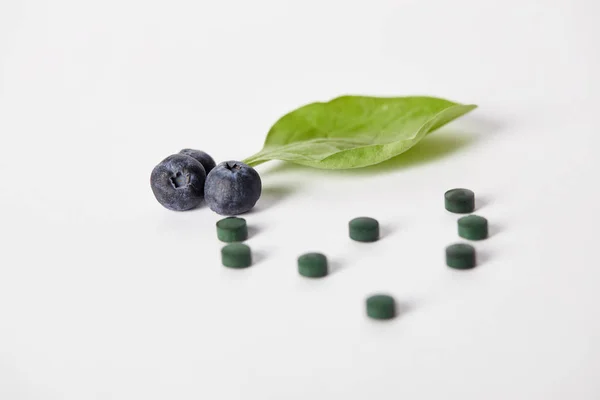 スピルリナ錠剤 ブルーベリーとミントの葉は白い背景の上のクローズ アップ表示 — ストック写真