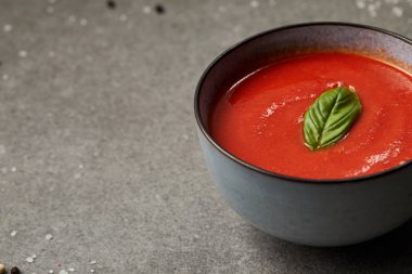 plate of appetizing tomato soup with basil on grey table clipart