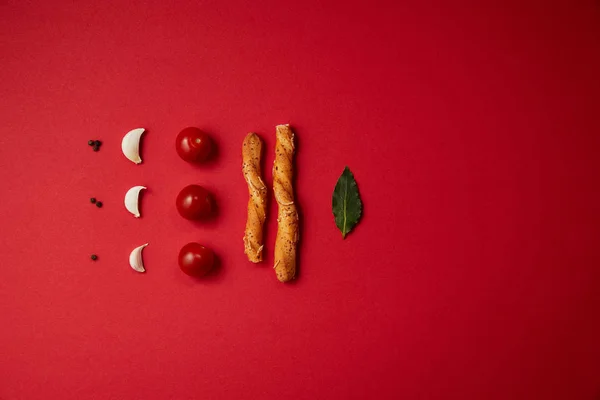Food styling of tasty tomatoes, garlic, bread sticks and bay leaf on red table — Stock Image Food Styling Tasty Tomatoes Garlic Bread Sticks Bay Leaf Red Stock Image