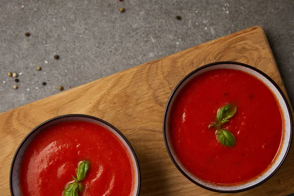 Top view of two plates with tomato soup on cutting board on grey table — Stock Image Top View Two Plates Tomato Soup Cutting Board Grey Table Stock Picture