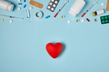 mavi yüzey üzerinde kalp ve çeşitli ilaçlar üstten görünüm
