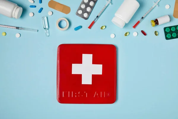 な薬と青い表面に赤の最初の援助キット ボックスのトップ ビュー — ストック写真