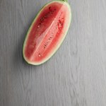 Top view of fresh watermelon cut half on grey wooden tabletop