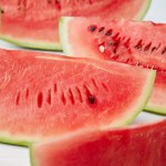 Close up view of arranged watermelon slices on white surface on blue backdrop