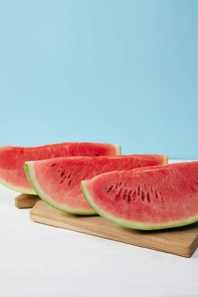 Close Van Gearrangeerde Watermeloen Segmenten Snijplank Witte Ondergrond Blauwe Achtergrond — Stockfoto