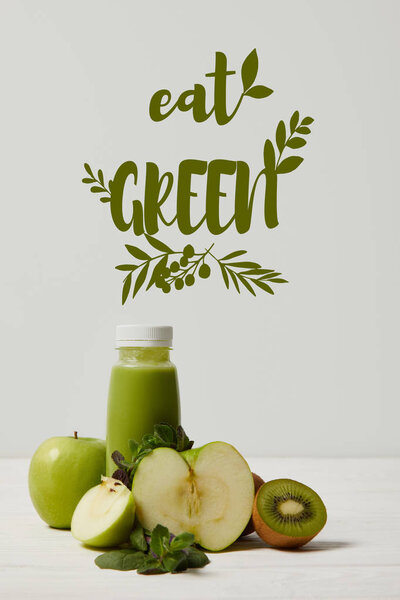 green detox smoothie with apples, kiwi and mint and on white wooden surface, eat green inscription