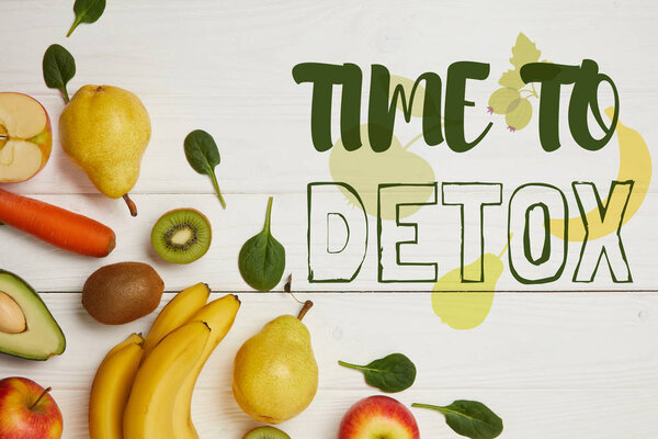 top view of fresh fruits and spinach leaves on white wooden background with copy space, time to detox inscription